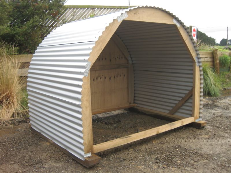 Curved large hen house made of ply wood and corrugated iron. Large front window, side entry door for humans and exterior accessible laying boxes